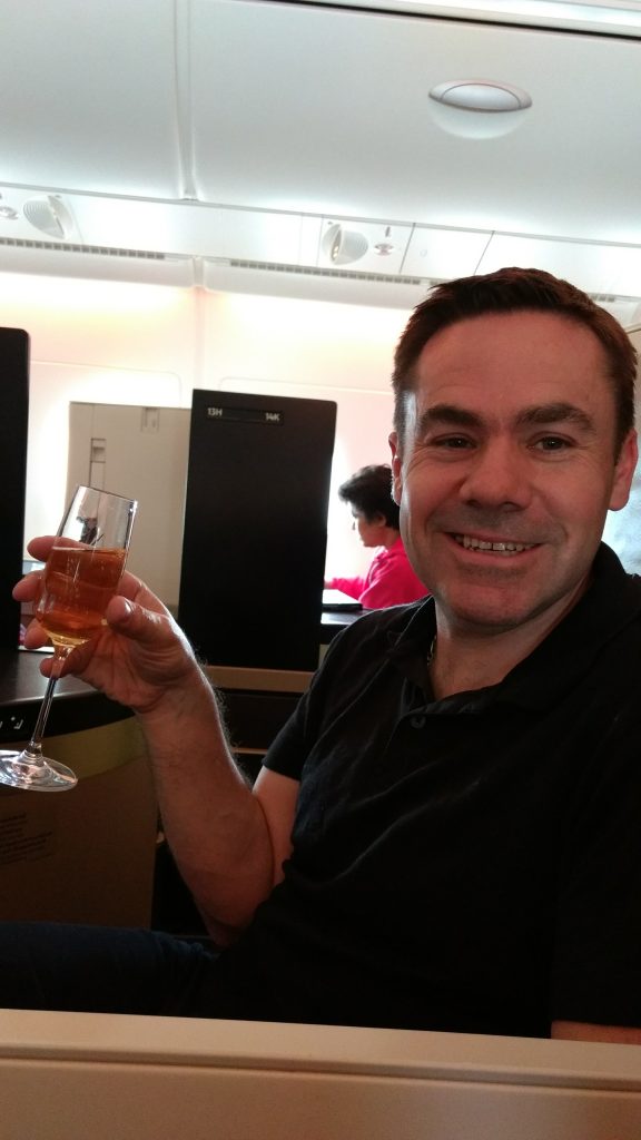 Me holding a glass of champagne in my  Etihad business class suite