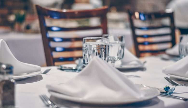 depth of field photo of clear drinking glass on white table near plate
