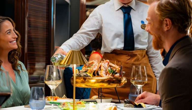 two people enjoying a meal in a restaurant on board the Enchanted Princess with their Princess Cruises package
